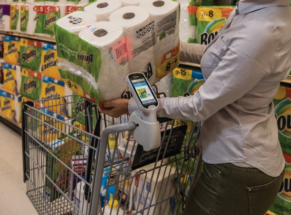 Shopper in retail store using self scan device to scan items